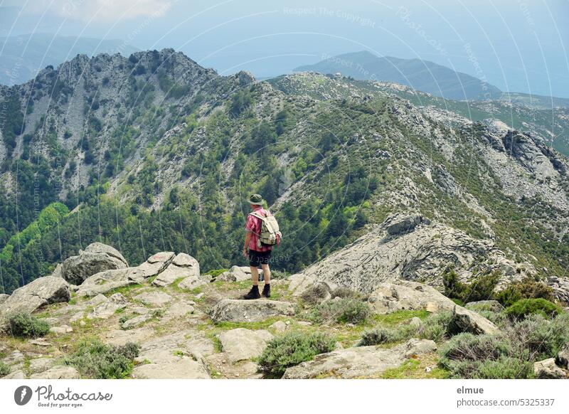 Hiker with backpack and hiking hat looks over the island of Elba from Monte Capanne Island hikers mountain Italy Blog Mediterranean sea Thyrrenian sea