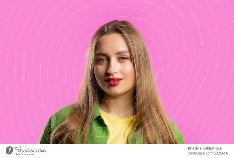 Pretty blonde woman portrait on pink studio background. Colorful outfit. Smiling adult attractive beautiful care cheerful close-up copy space expression eyes