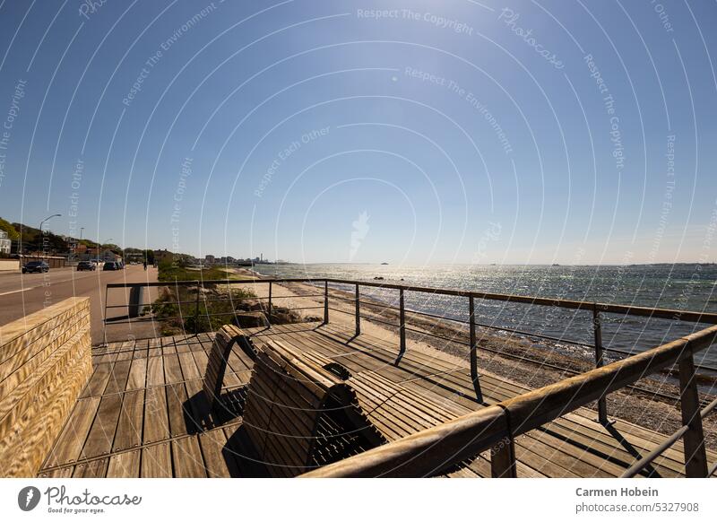 Wooden deck chairs on the promenade overlooking the sea to relax under a blue sky and bright sunshine Outdoors Summertime Weekend Bright bank coast Nature