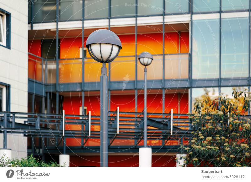 Street lamps in front of red-gray rectangular facade streetlamp Lantern Street lighting 1970s '60s Modern Red Gray Architecture urban bleak Banal colored bush