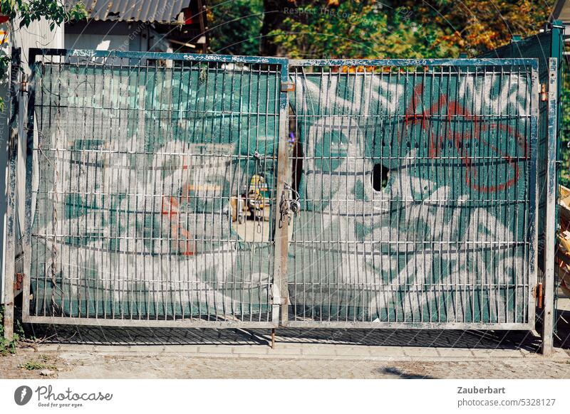 Closed steel gate with tarpaulin for privacy protection, graffiti on it Goal Steel yard gate Screening Graffiti Pattern Contrast Hideous bleak Gloomy urban