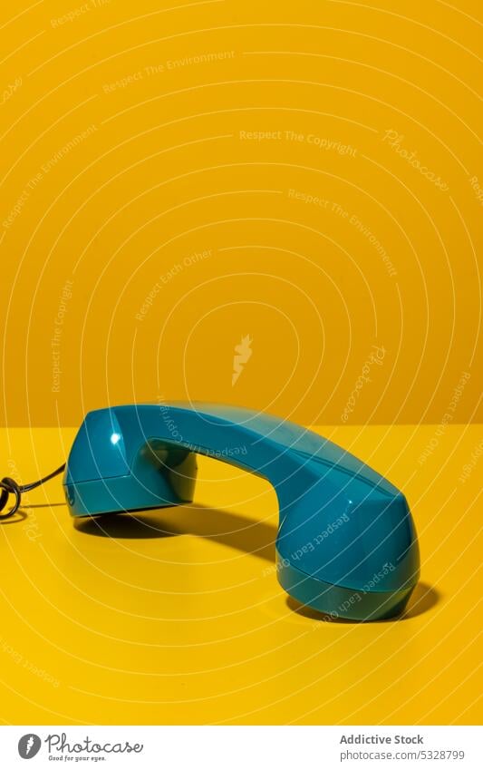 Handset of retro phone off hook on yellow desk handset stationary telephone phone call contact communicate cable cord wire old fashioned vintage plastic line