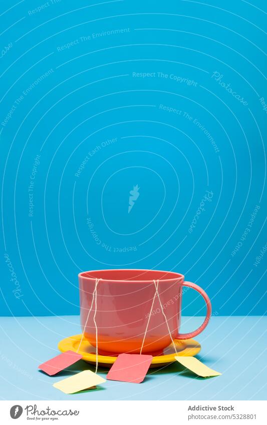 Pink ceramic mug with tea bags on blue background cup drink saucer bright colorful yellow beverage design vivid hot drink porcelain vibrant simple dishware