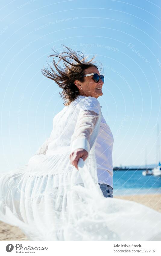 Woman spinning around on pier on sunny day woman sea walk boardwalk spin around wave vacation outstretch cloak coast stroll shore water summer walkway nature