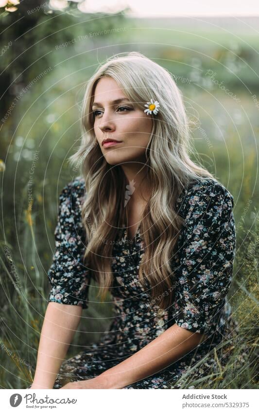 Pensive woman sitting on grass nature rest thoughtful calm pensive field dreamy ponder think countryside serious blond female young casual summer style rural