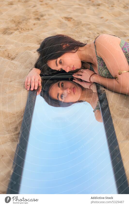 Woman lying on sand near mirror woman pensive thoughtful beach reflection calm seashore tranquil female young long hair nature peaceful brunette coast seaside