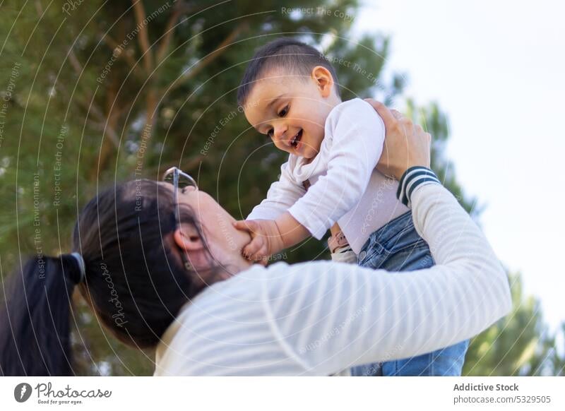 Happy mother lifting adorable little son in air woman boy play park weekend love having fun kid toddler child cute parent together happy playful joy stripe