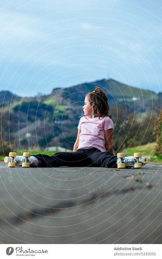 Little girl with roller skaters resting on road kid relax summer countryside childhood weekend leisure activity ride tree daytime nature enjoy recreation