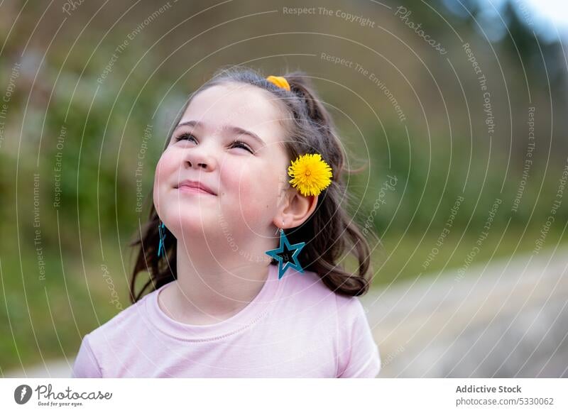 Happy girl standing with yellow flowers in hair kid ear earring park smile happy nature summer cute child cheerful little bright positive joy adorable bloom