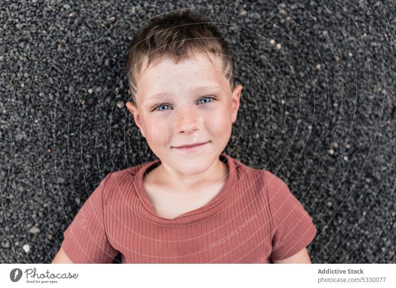 Pensive boy lying on stony shore and looking away summer dreamy thoughtful smile beach vacation pensive happy rest stone relax child nature calm seashore