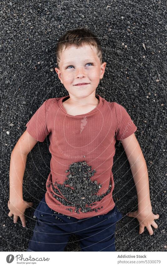 Pensive boy lying on stony shore and looking away summer dreamy thoughtful smile beach vacation pensive happy rest stone relax child nature calm seashore