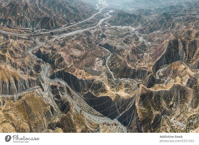 Drone view of rough rocky mountains with dry river in daylight highland nature valley drought arid uneven desert ridge barren terrain flow formation range