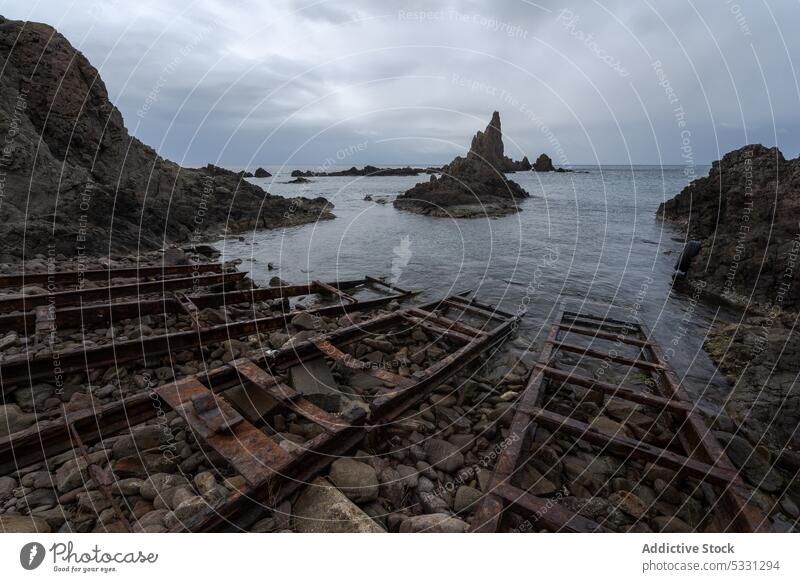 Rocky seashore with boat rails on gloomy day cliff storm cloudy coast beach rocky rough ripple nature seascape sky ocean cabo de gata arrecife de las sirenas