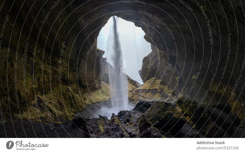 Amazing flowing waterfall in mountainous cave landscape nature cascade stream formation stone rocky grass rapid terrain wild cliff rough spectacular power slope