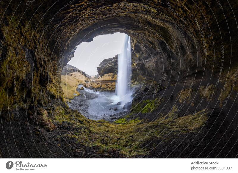 Amazing flowing waterfall in mountainous cave landscape nature cascade stream formation stone rocky grass rapid terrain wild cliff rough spectacular power slope