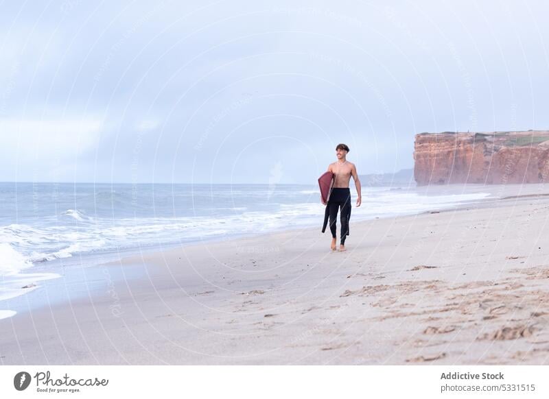 Distant surfer walking on sandy seacoast man beach smile surfboard sunset glad vacation summer wave holiday happy male ocean shirtless shore water seashore