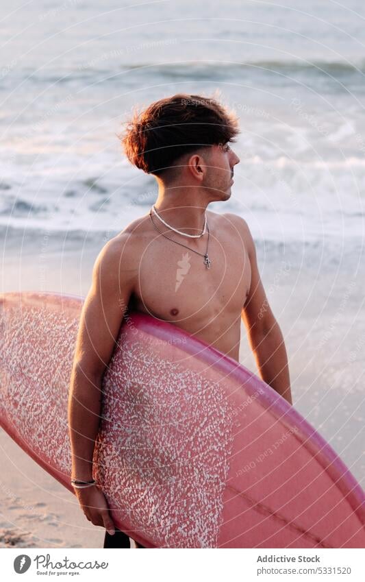 Distant surfer walking on sandy seacoast man beach surfboard sunset vacation summer wave holiday male ocean shirtless shore water seashore carry hobby resort