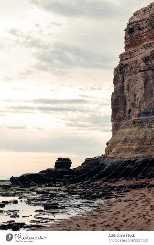 Rocky cliff near sea under cloudy sky beach rocky nature coast sunset shore rough water ocean stone evening formation seashore seaside picturesque scenic