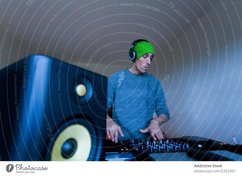 Man playing on DJ mixing console at home man dj music mixer sound equipment beanie audio controller button entertain record switch contemporary electronic