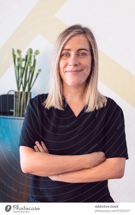 Smiling woman with crossed arms and in scrubs smile professional portrait medic doctor physiotherapist uniform content specialist confident office staff