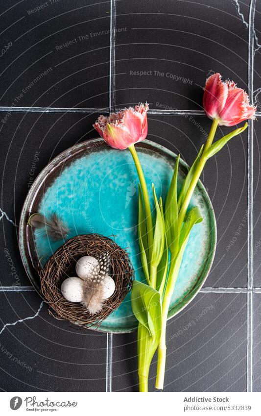 Table setting with seasonal flowers on concrete background easter tulip dinnerware eggs table beautiful ceramic cutlery dark daytime eat eating festive floral