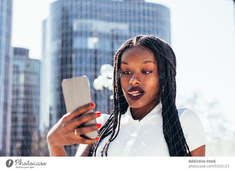 Black woman taking selfie on smartphone using self portrait street device mobile tongue cellphone take photo city bench casual african american female ethnic