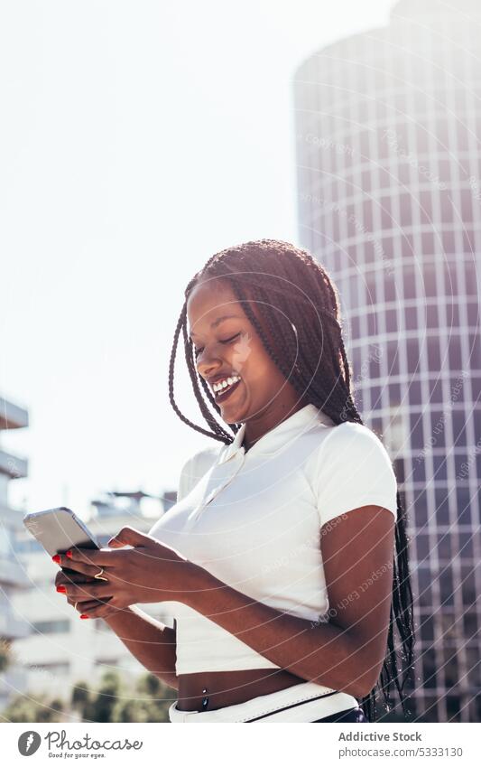 Cheerful black woman using smartphone on street cool smile browsing positive message happy surfing cellphone cheerful modern ethnic female african american