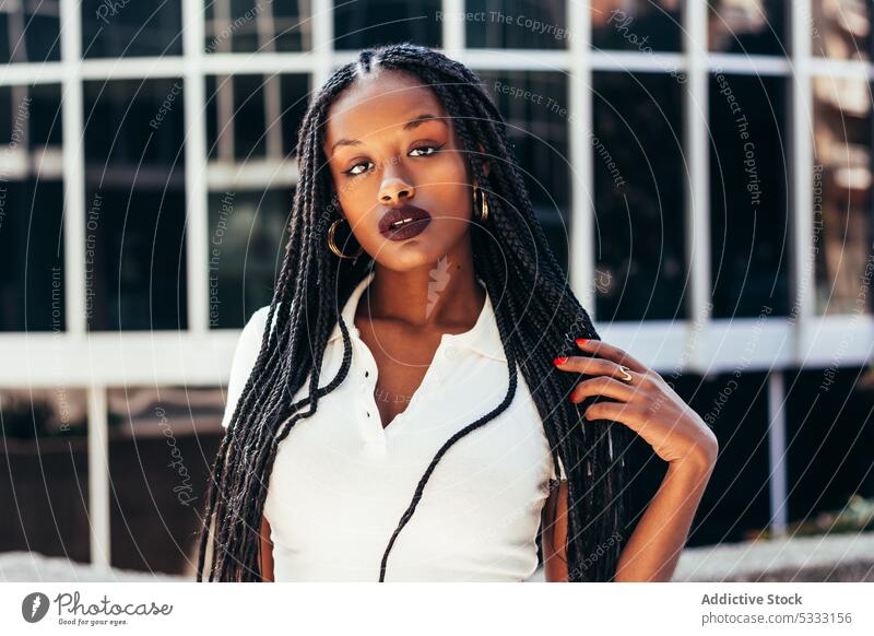 Black woman with long braided hair on street portrait stare urban trendy cool gaze emotionless individuality self assured afro braids style ethnic female young