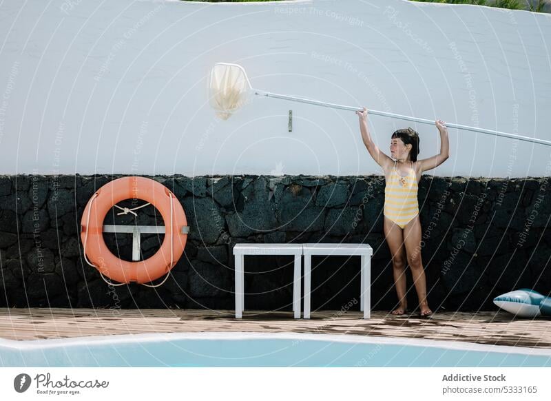 Little kid using pool skimmer net girl clean water surface vacation barefoot child childhood yard summer poolside holiday resort clear activity hygiene aqua wet