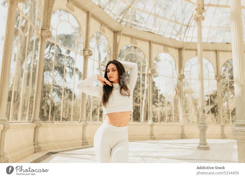 Pensive woman dancing in glass building and looking away dance thoughtful arm raised dreamy pensive calm long hair dark hair glass palace buen retiro park