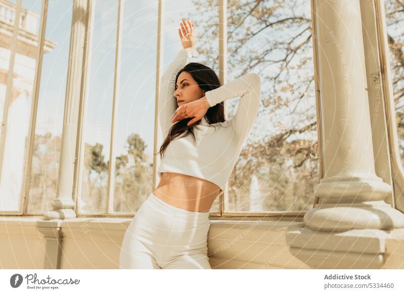 Pensive woman dancing in glass building and looking away dance thoughtful arm raised dreamy pensive calm long hair dark hair glass palace buen retiro park