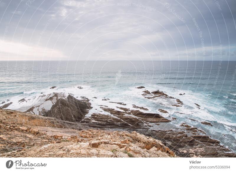 Rocky cliffs with futuristic patterns on the Atlantic coast near the town of Aljezur in southwestern Portugal. The sound of the ocean as the sun sets. Wandering the Rota Vicentina