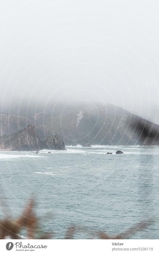 Portugal's western coastline of rocky cliffs and sandy beaches in the Odemira region. Wandering along the Fisherman trail on rainy days splash stormy weather