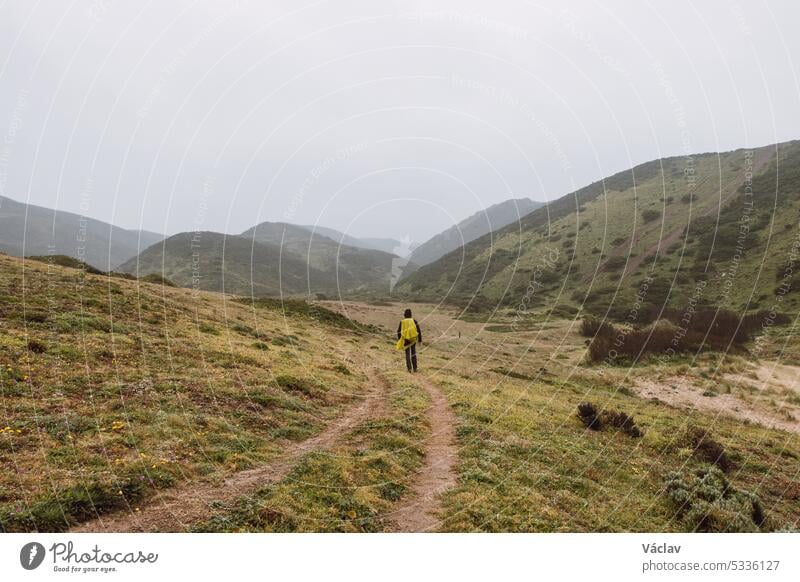 Wandering in heavy rain and wearing a raincoat along the Fisherman Trail in the southern part of Portugal during rainy weather heading to Cape St. Vicente. Rough landscape