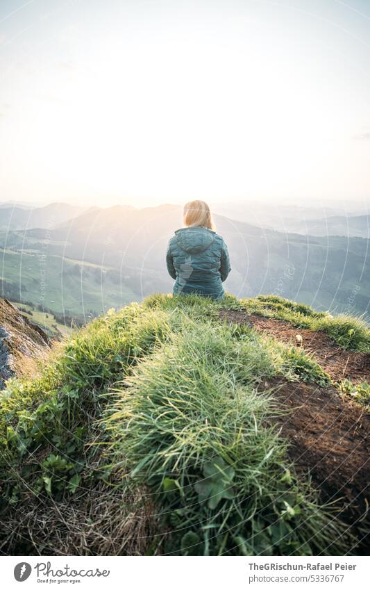 Woman sitting on rocky ledge looking into sunset Switzerland appenzellerland Exterior shot Tourism Mountain Colour photo Alpstein Nature Sun Grass