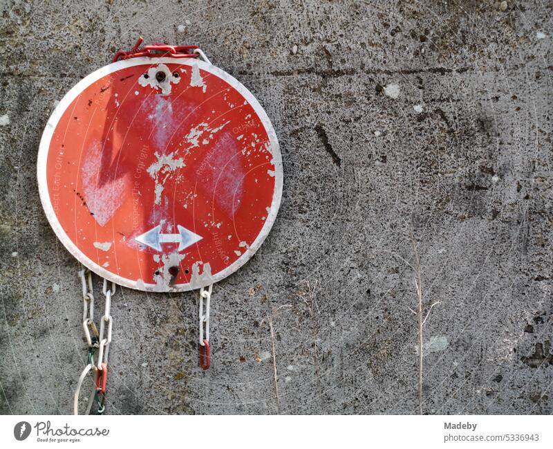 Old rundown round traffic sign in red with arrows in no stopping on gray wall in a backyard in Bielefeld in the Teutoburg Forest in East Westphalia Lippe Sign