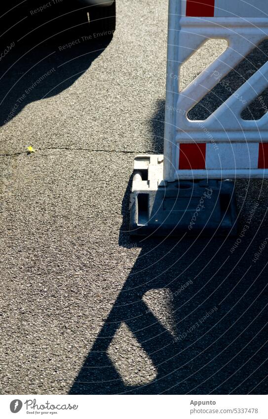 Detail of road asphalt with light and shadow patterns on a white and red road beacon Asphalt asphalt surface road surface Gray Road beacon Warning beacon