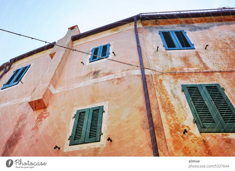 living on Elba - winding bright residential building with shutters in front of the windows from the frog perspective Apartment Building Poggio Italy Island Blog