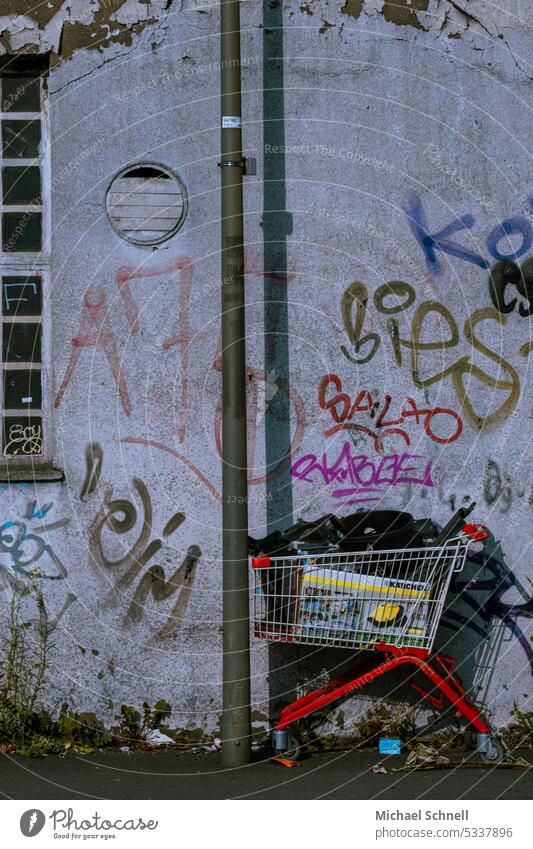 Parked shopping cart with packages in front of wall with graffiti Shopping Trolley Graffiti Consumption Metal Colour photo Retail sector Supermarket Trade