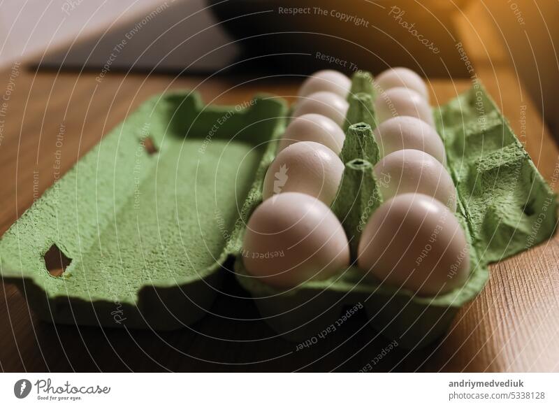 Dozen white fresh chicken eggs in the green cardboard egg tray on wooden table background. Fresh organic eggs in open carton pack or egg container. Nutritious food. Farm's products concept