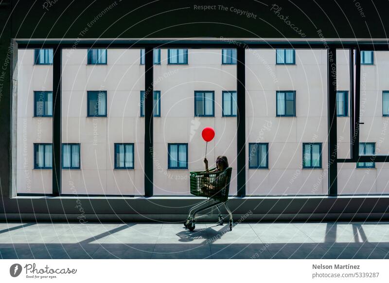 Girl inside a shopping cart holding a balloon backlit silhouette innocence wonder childhood adventure hope joy imagination exploration light shadows dream