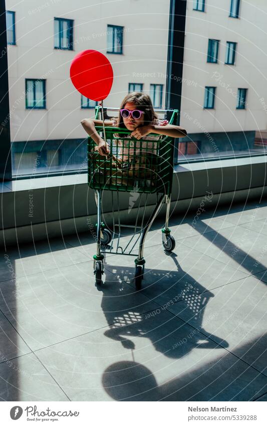 Girl inside a shopping cart holding a balloon backlit silhouette innocence wonder childhood adventure hope joy imagination exploration light shadows dream