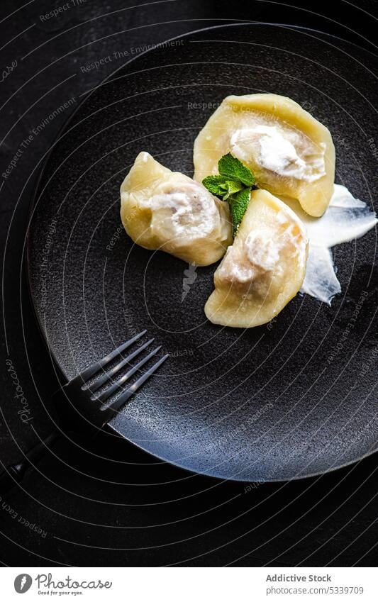 Tasty traditional Ukrainian dumplings with cherry food cream sour ukraine dark black background boiled bowl ceramic cutlery desert dish fork fresh gourmet lunch