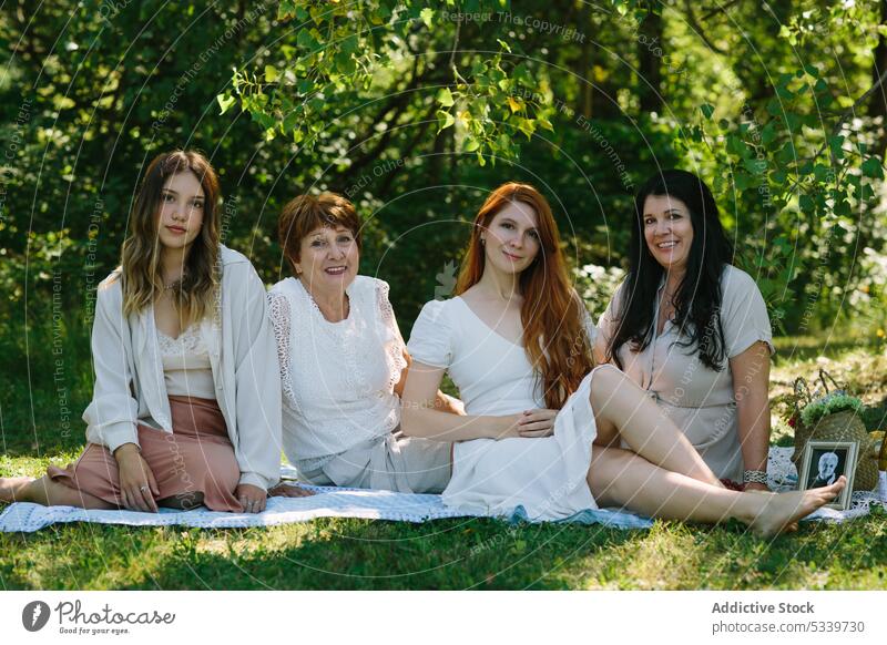 Cheerful women resting on blanket in park summer picnic frame smile photo together happy cheerful female grandmother daughter granddaughter positive weekend