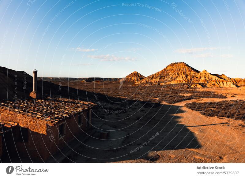 Old stone building in sunny desert mountain uneven nature rock cliff rough formation landscape dry terrain aged surface hill architecture ridge old highland