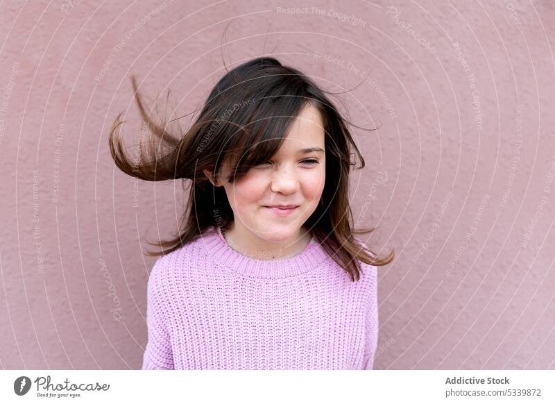 Cute child in sweater standing with flying hair kid smile happy adorable childhood cute glad joy preteen girl positive cheerful appearance delight charming