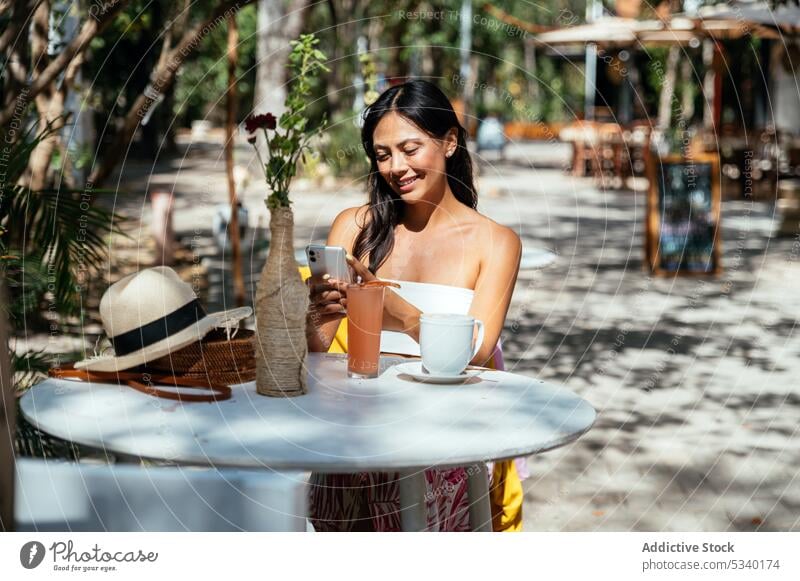 Focused woman browsing smartphone in outdoor cafe beverage cup hot drink concentrate message tulum mexico asian mexican using gadget device coffee mobile female