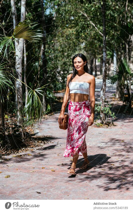 Content woman walking on pathway between tropical palms summer exotic nature style street tranquil female young calm tulum mexico mexican asian road travel