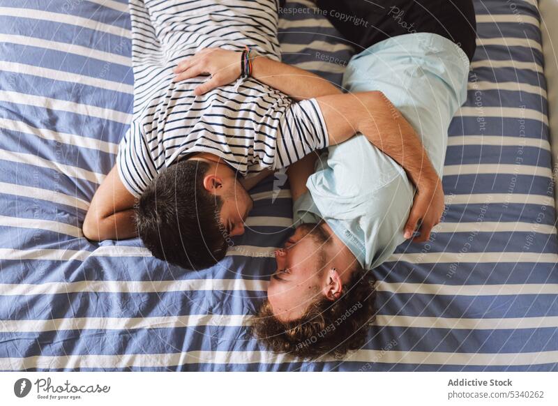 Loving gay couple kissing and hugging on bed cuddle love together relationship home affection embrace tender bonding romantic homosexual gentle boyfriend caress