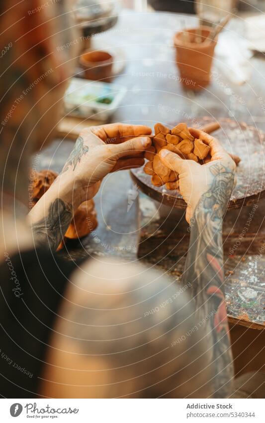 Man creating clay bowl on wheel in workshop man pottery concentrate shape craft skill craftsman artisan ceramic creative handmade studio young process tattoo